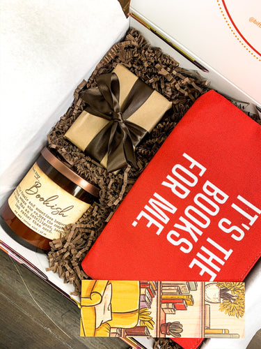Gift box that includes trivia game cards on Black Authors, a candle titled Bookish and wooden bookmark and a book pouch in red that reads, "it's the books for me"